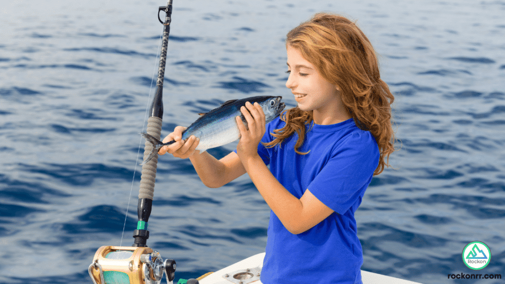 kid holding a fish on a fishing boat