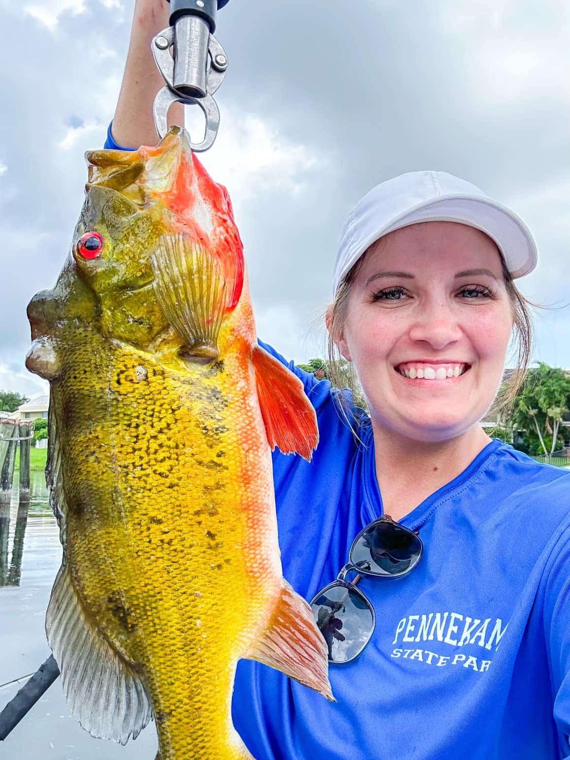 happy lady holding up a peacock bass florida